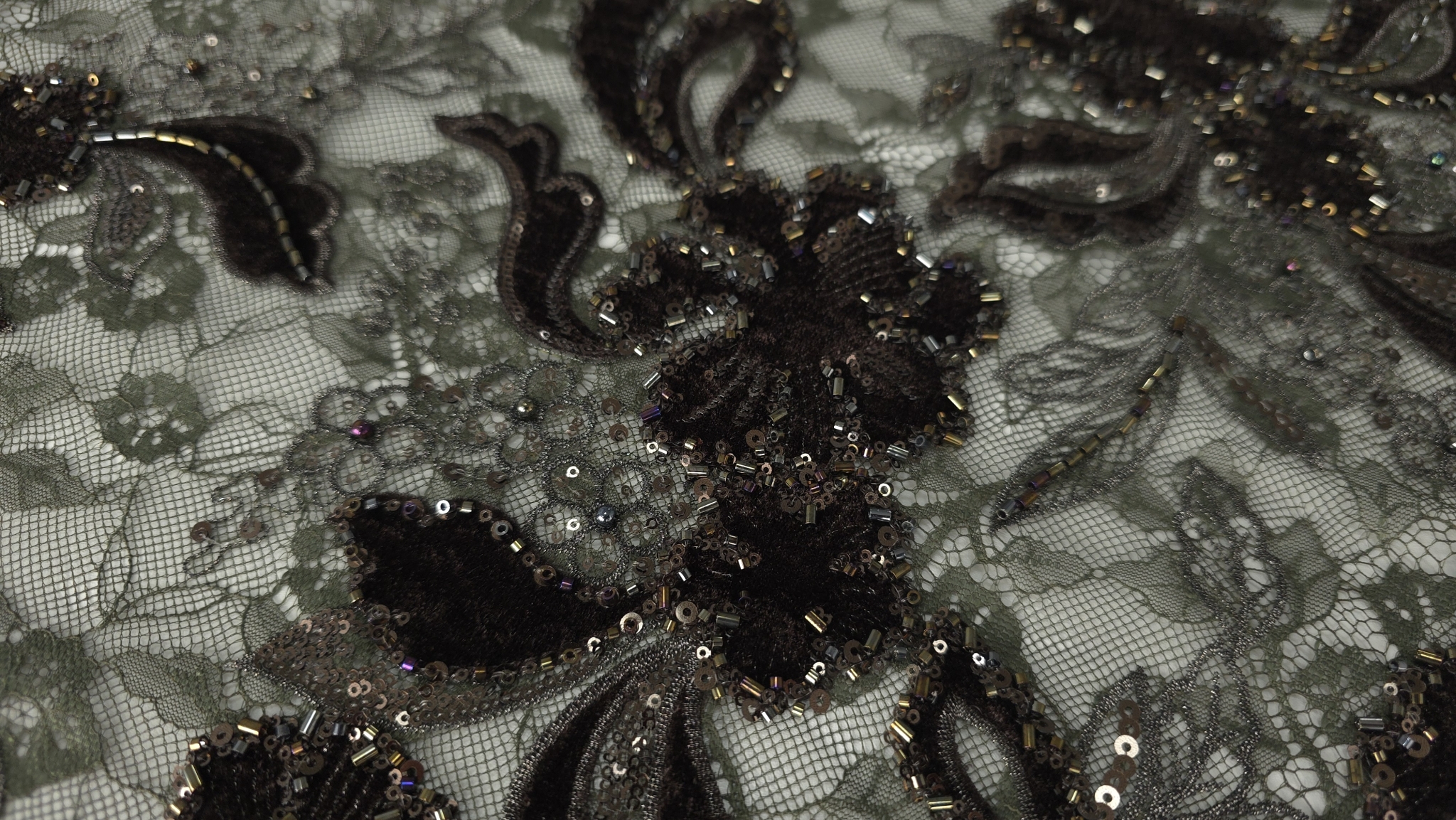 Falduri ale materialului cu micropaiete și margele vizibile pe contur