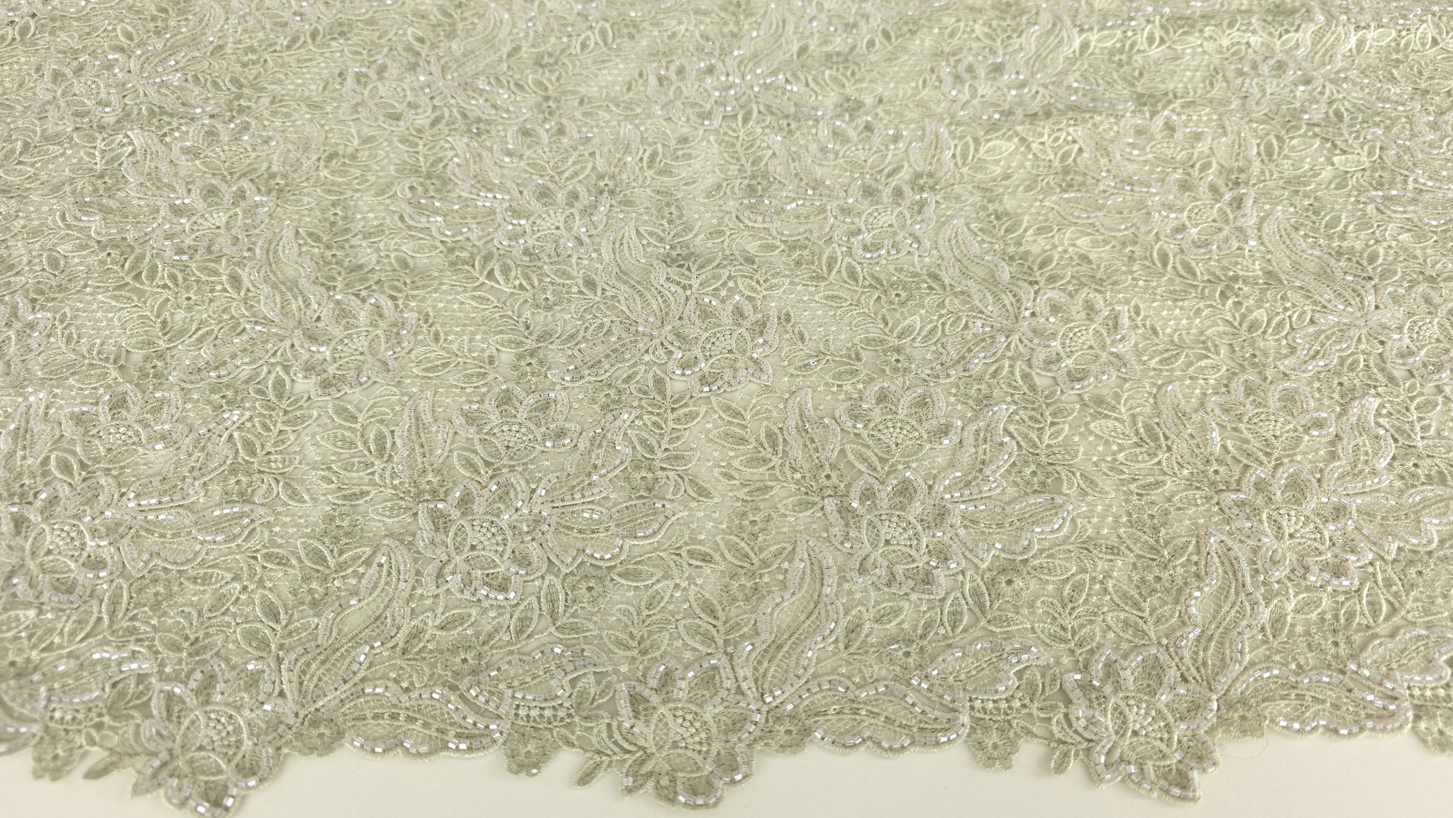 Falduri ample de material brodat cu joc de lumini între contururi