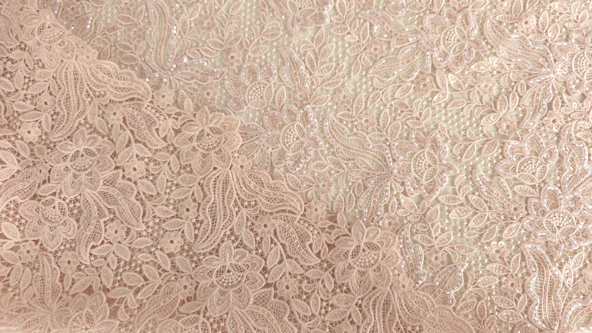 Dantelă brodată roz accesorizată cu margele formând falduri în lumină caldă