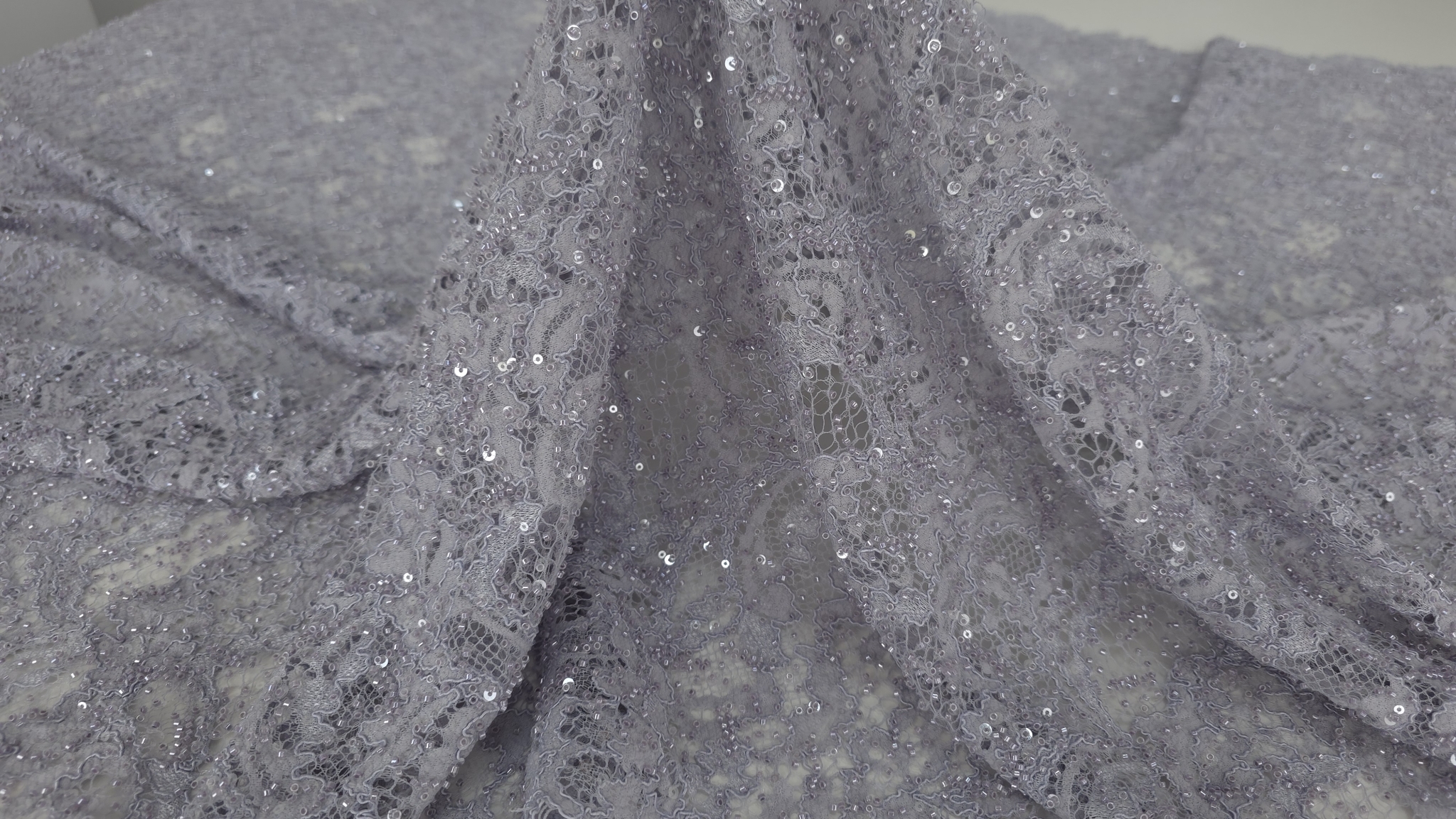 Falduri ample pe material textil cu străluciri subtile din aplicații fine