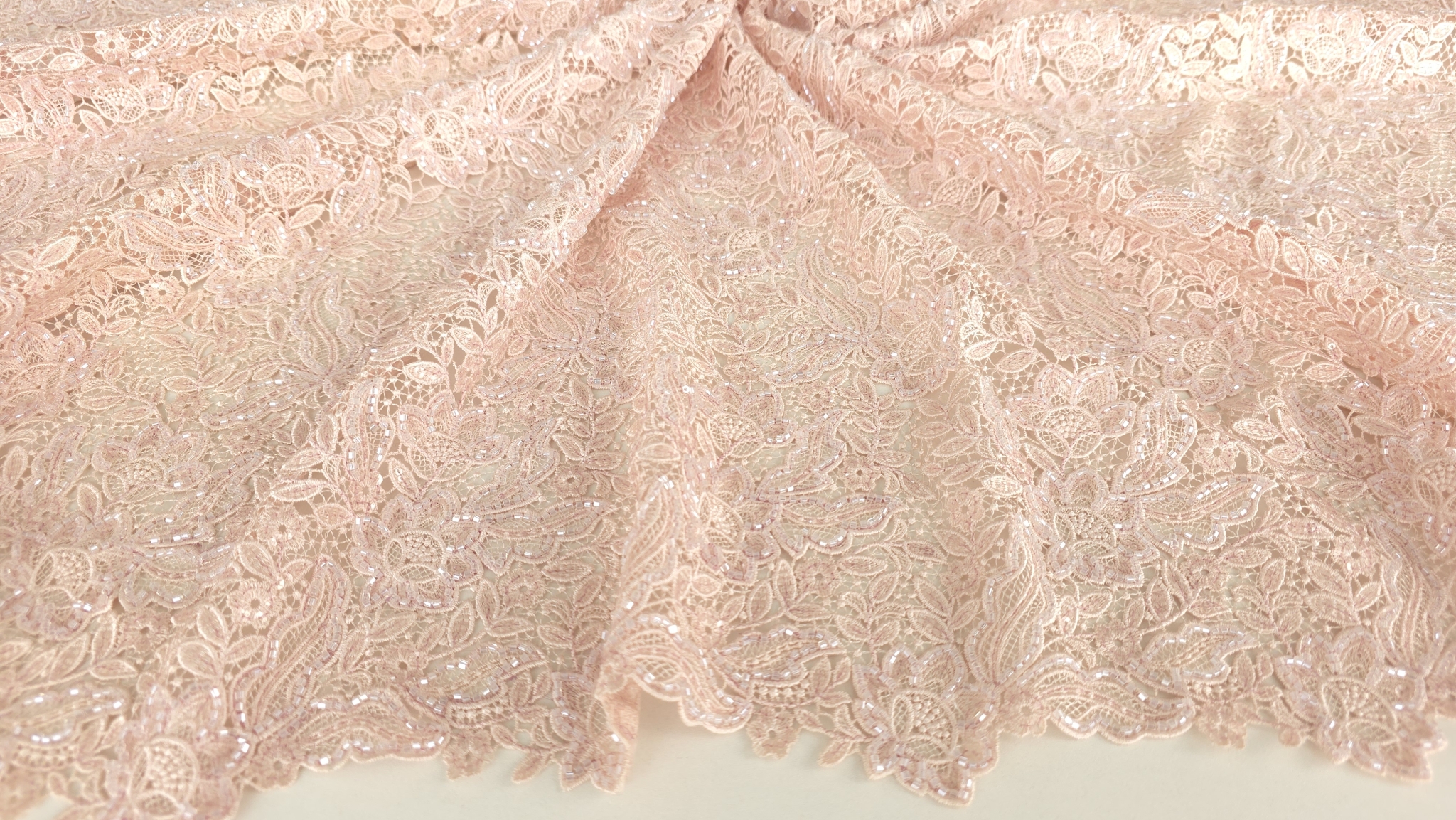 Broderie roz pastel cu margele prezentată în plan general pe suprafață albă