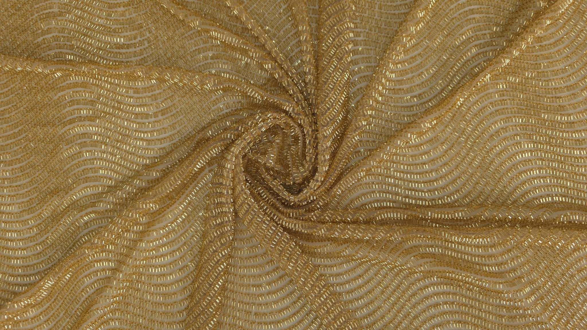 Falduri răsucite în spirală pe material auriu cu desen ondulat dens