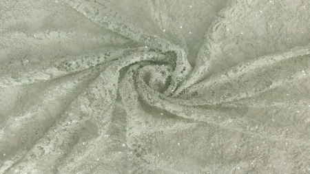 Falduri răsucite în spirală pe material verde pastel cu broderie florală și străluciri fine de paiete