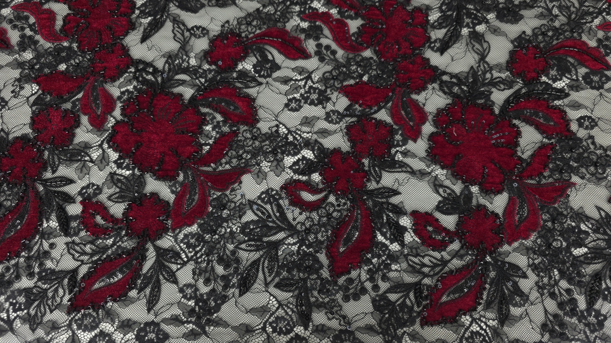 Floare mare din catifea roșu sânge cu frunze pe fond de tulle negru transparent