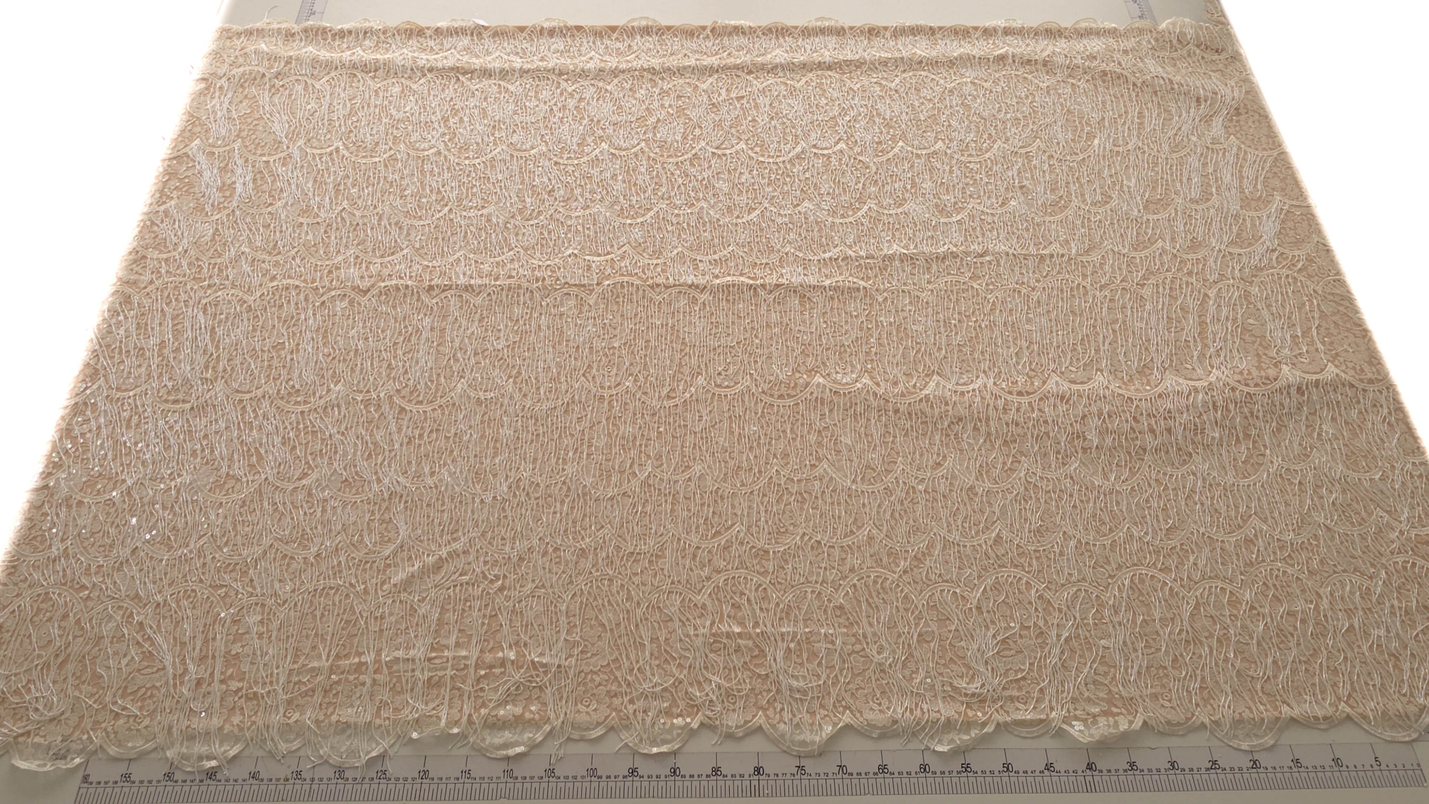 Lățimea completă a materialului prezentată cu riglă de croitorie și ambele borduri festonate vizibile