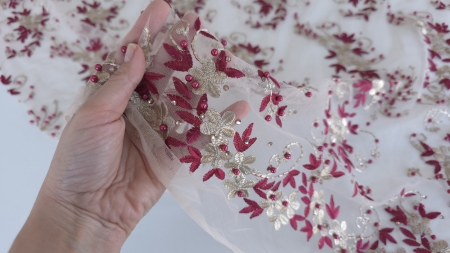 Mana care tine marginea unei dantele brodate cu margele pe tulle