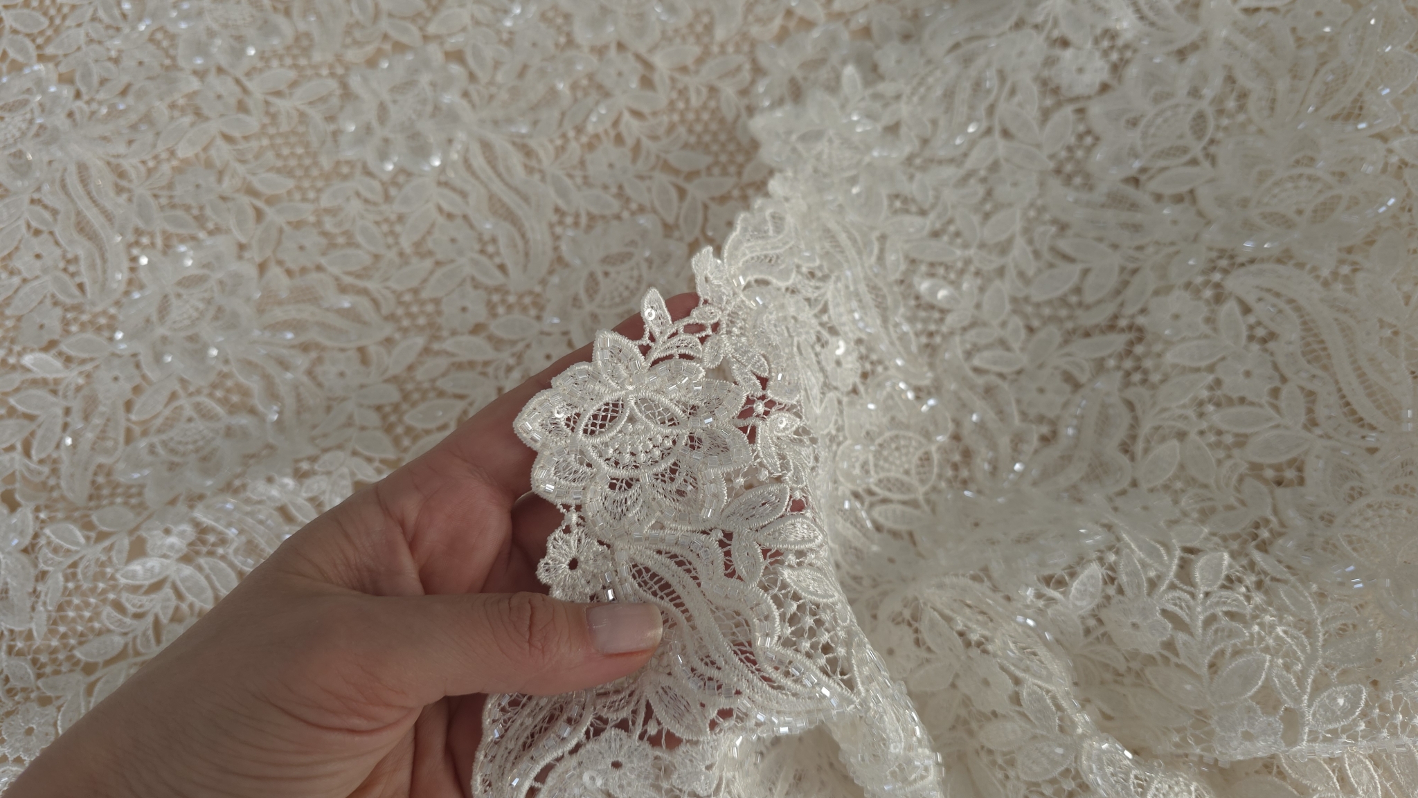 Mână plasată sub broderie ivory pentru a evidenția gradul de transparență