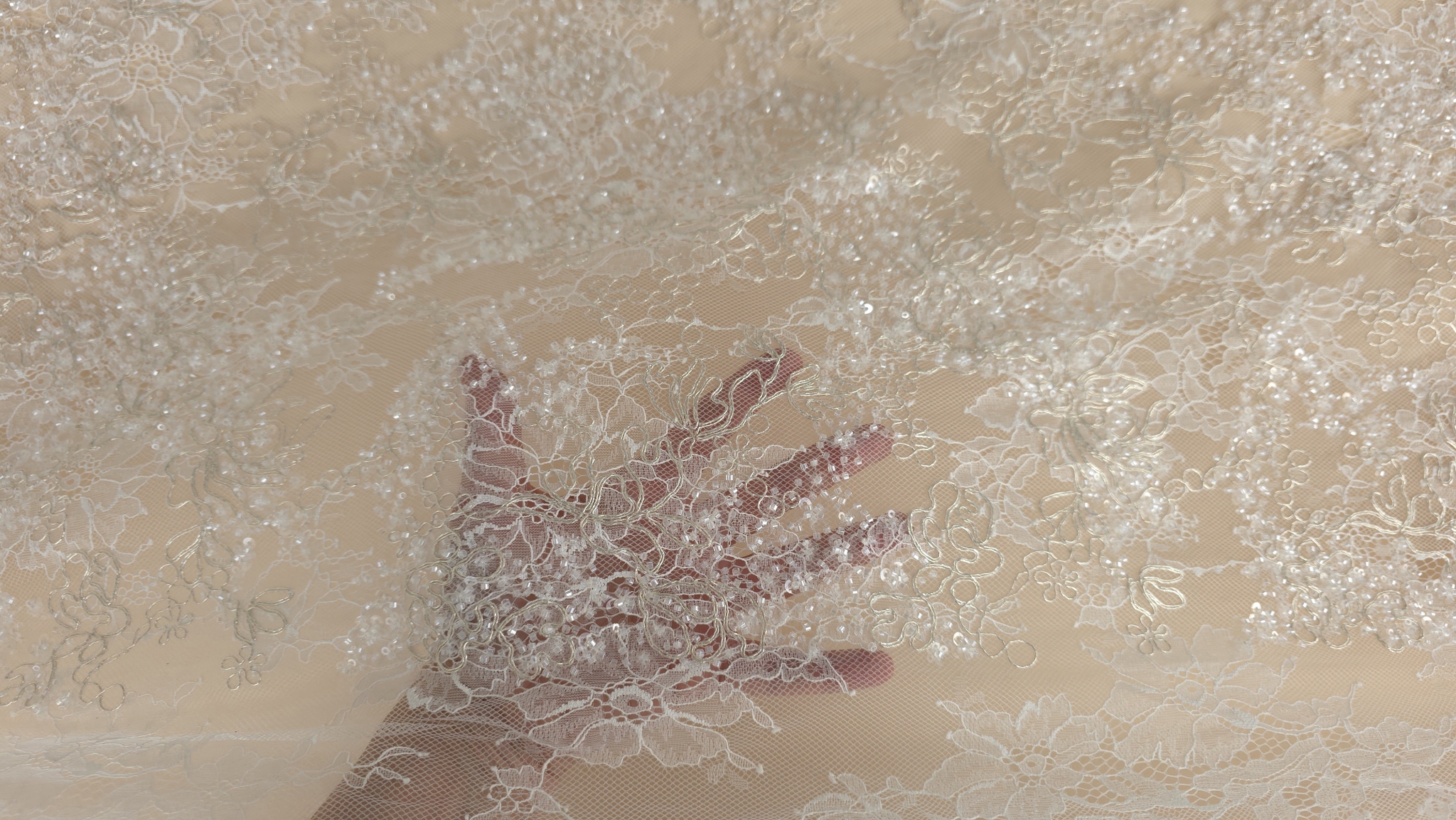 Mână plasată sub țesătură ivory pentru a sublinia conturul luminos și baza netedă