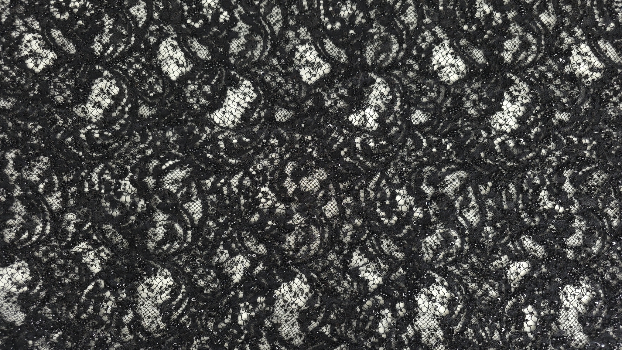 Mână plasată sub țesătură neagră evidențiind contrastul cu pielea