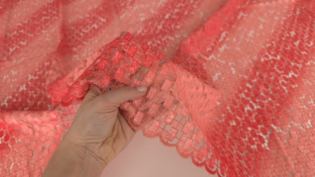 Mână prezentând bordura scalop a broderiei roșii degrade cu paiete pe fundal transparent