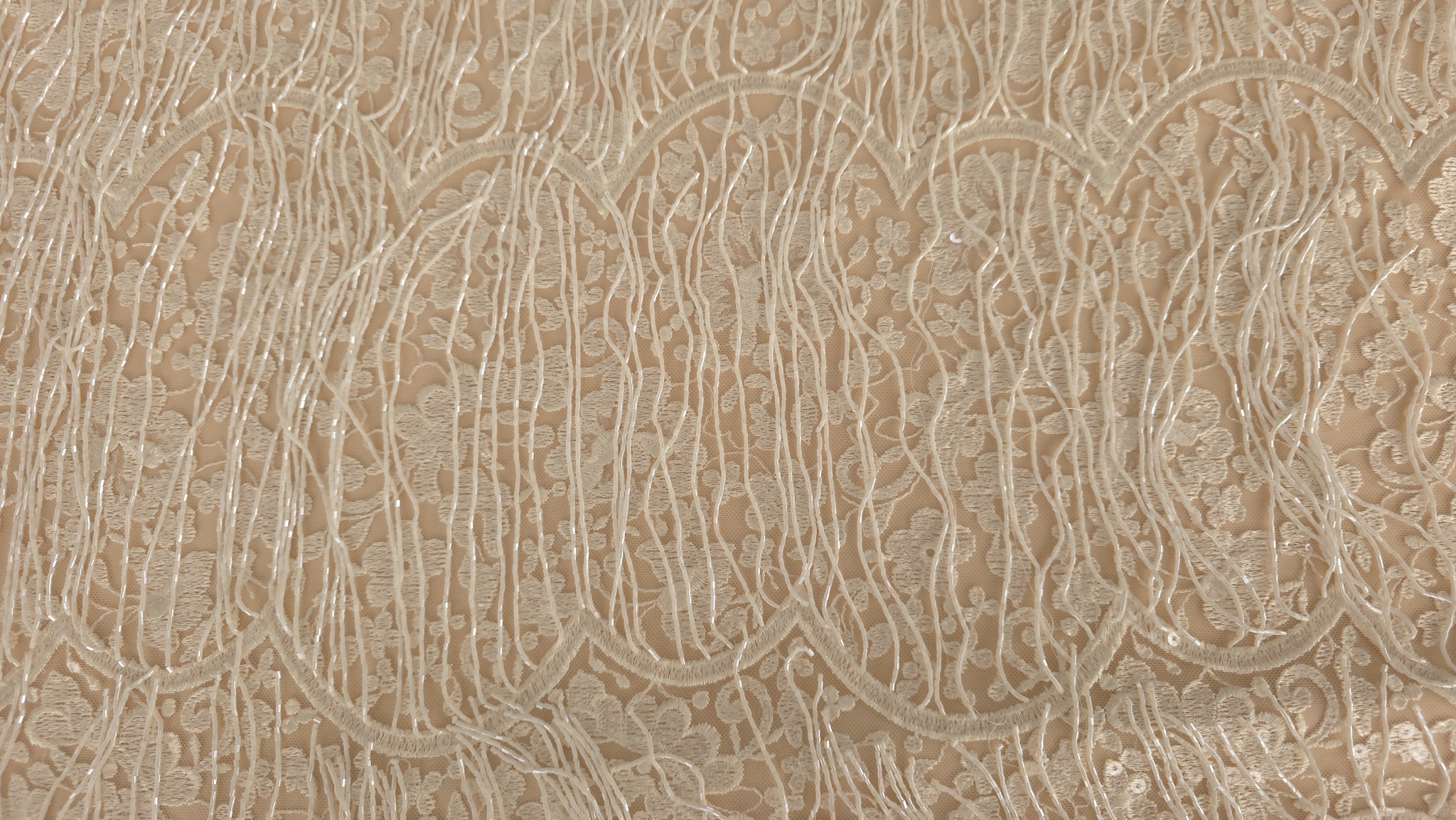 Mână prezentând colțul dantelei brodate cu franjuri de mărgele căzând liber