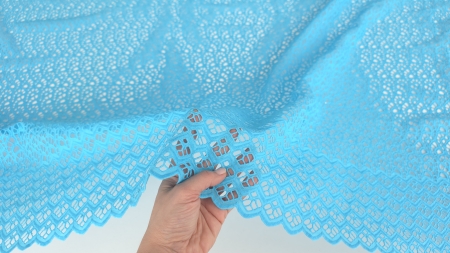 Mână ridicând bordura dantelei turcoaz brodate cu cristale, detaliu scalop și romburi