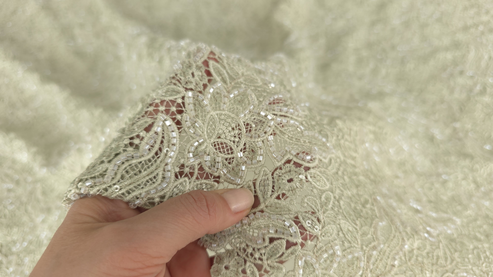 Mână ridicând colțul materialului pentru a arăta spațiile deschise dintre motive