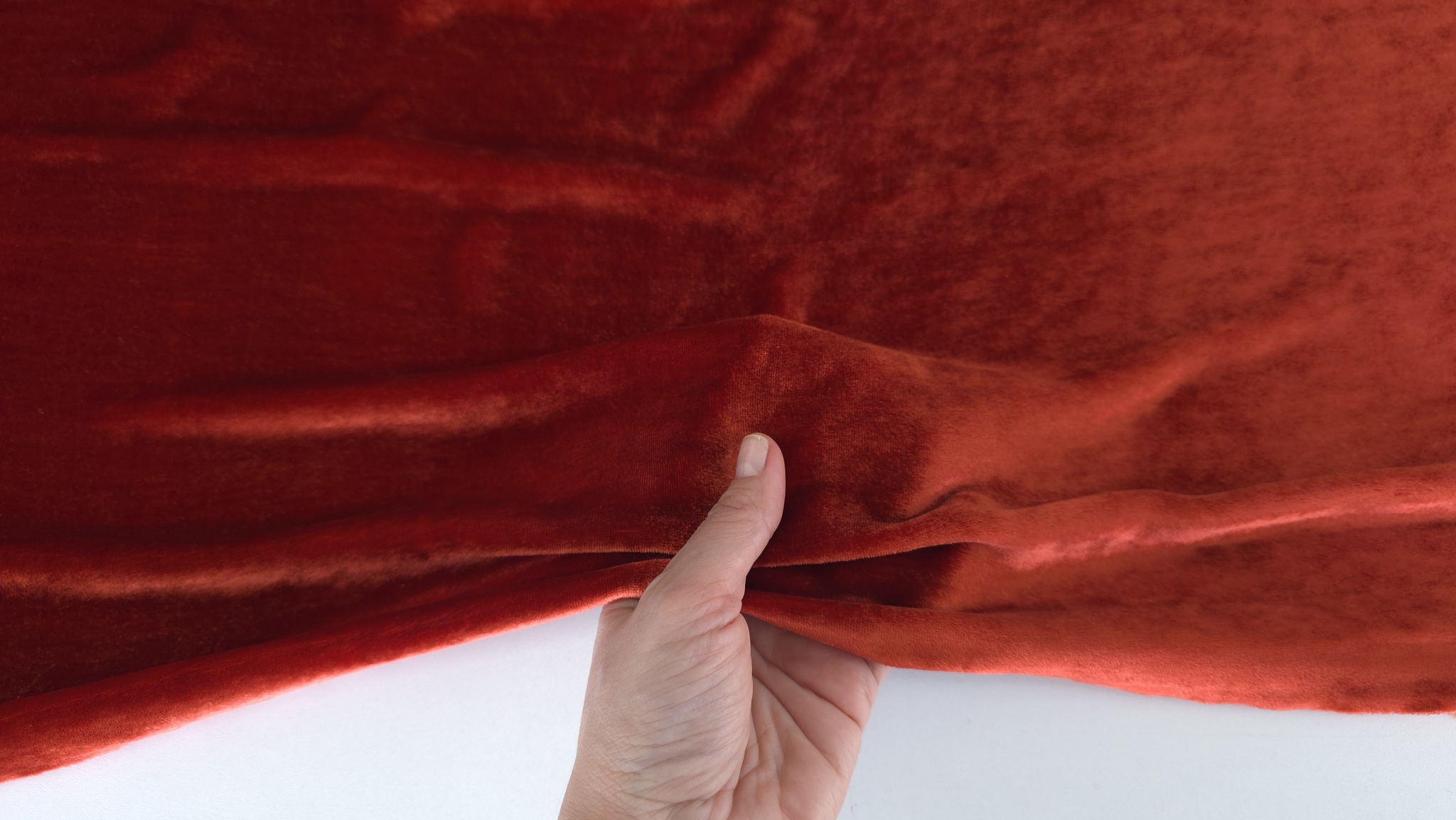 Mână ridicând marginea de catifea grenadine arătând fața și dosul