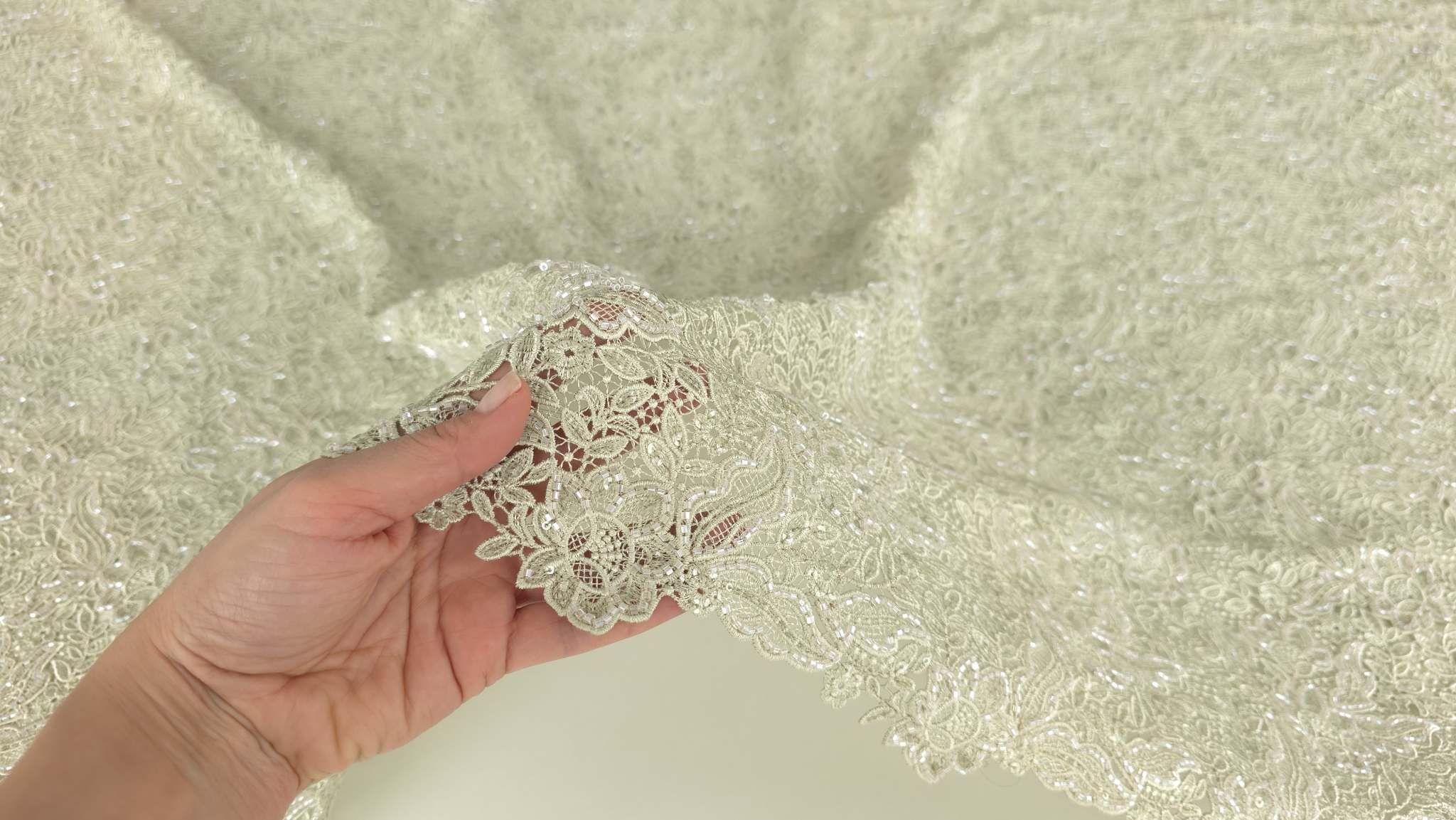 Mână ridicând marginea materialului pentru a arăta spațiile deschise dintre motive