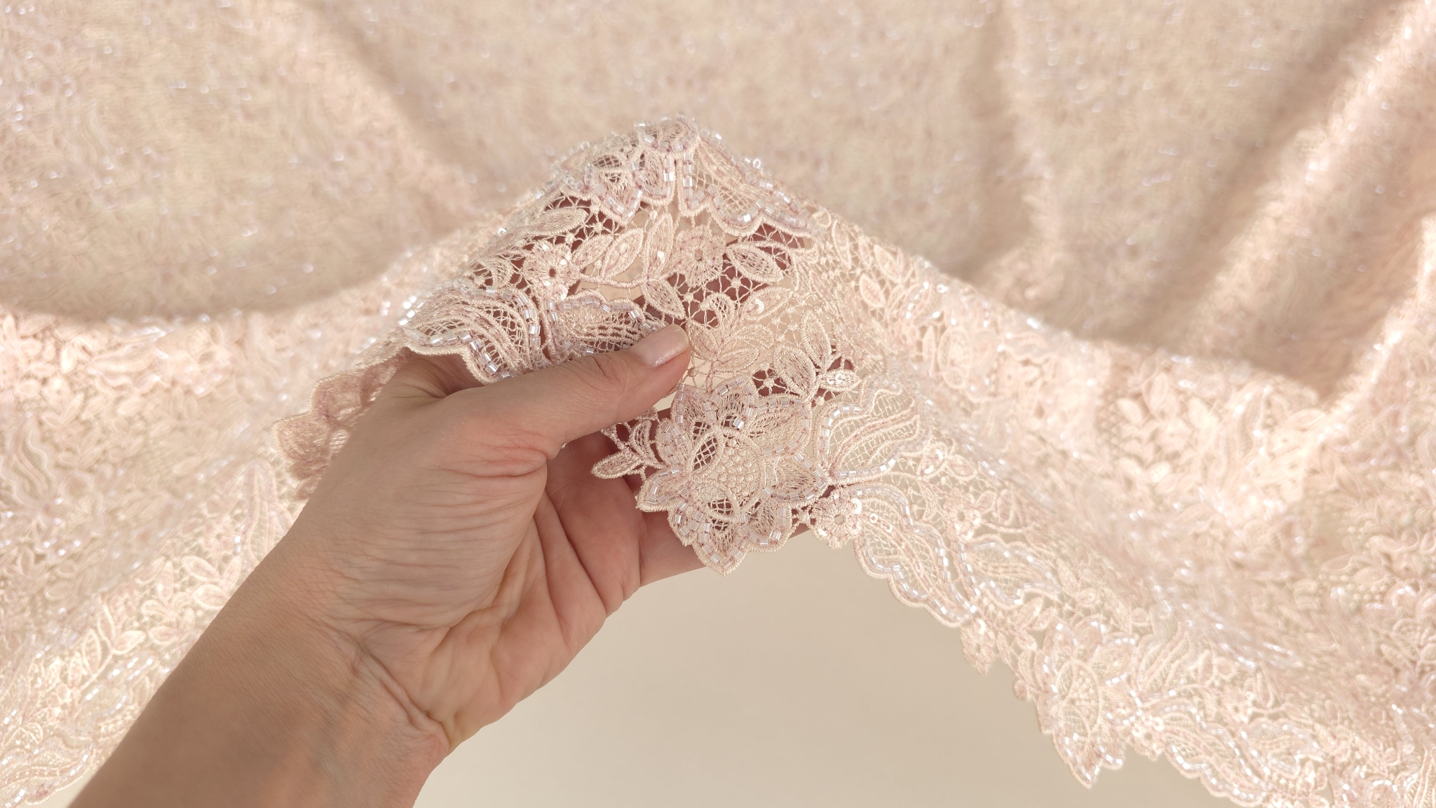 Mână ridicând materialul arătând transparența fondului de tul