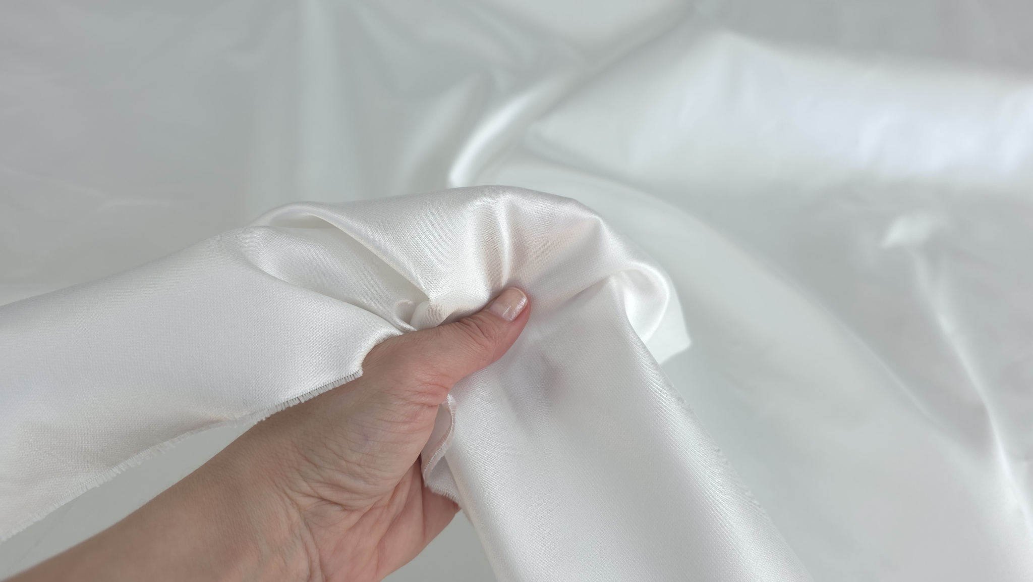 Mână ținând marginea materialului ivory pentru a arăta opacitatea