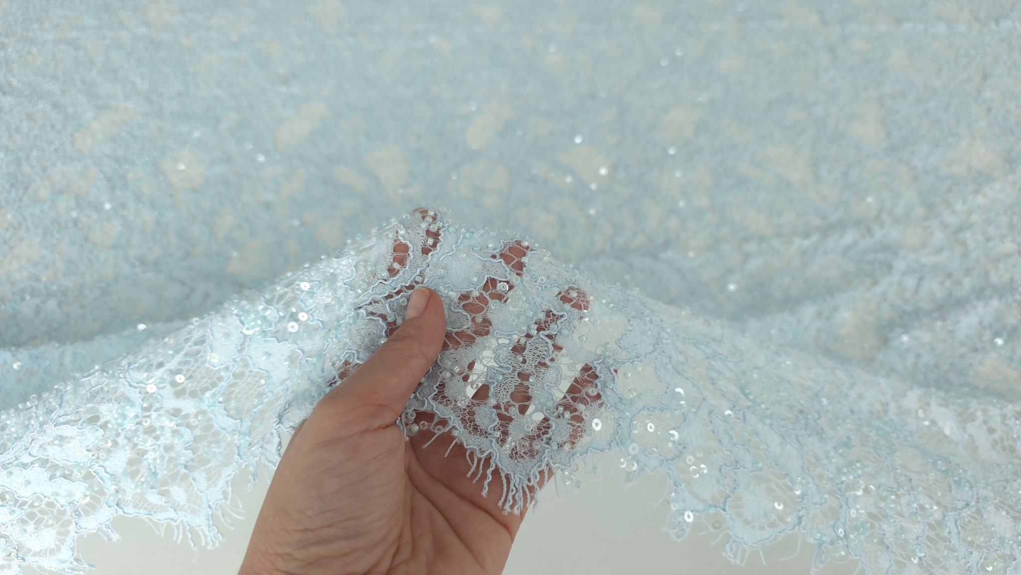 Mână ținând materialul pentru evidențierea transparenței tului fin