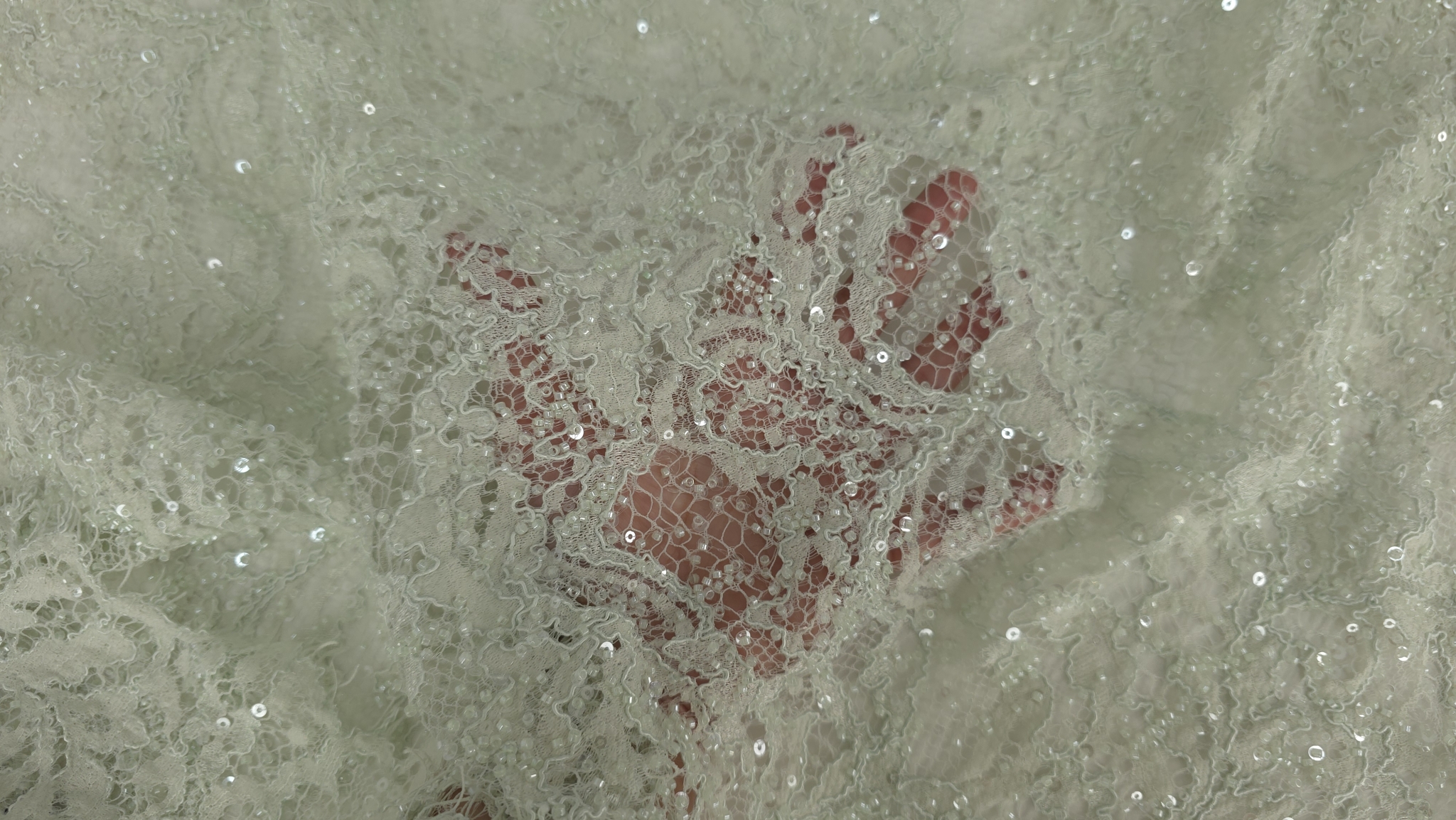 Mână ținând materialul verde pastel pentru evidențierea transparenței tului