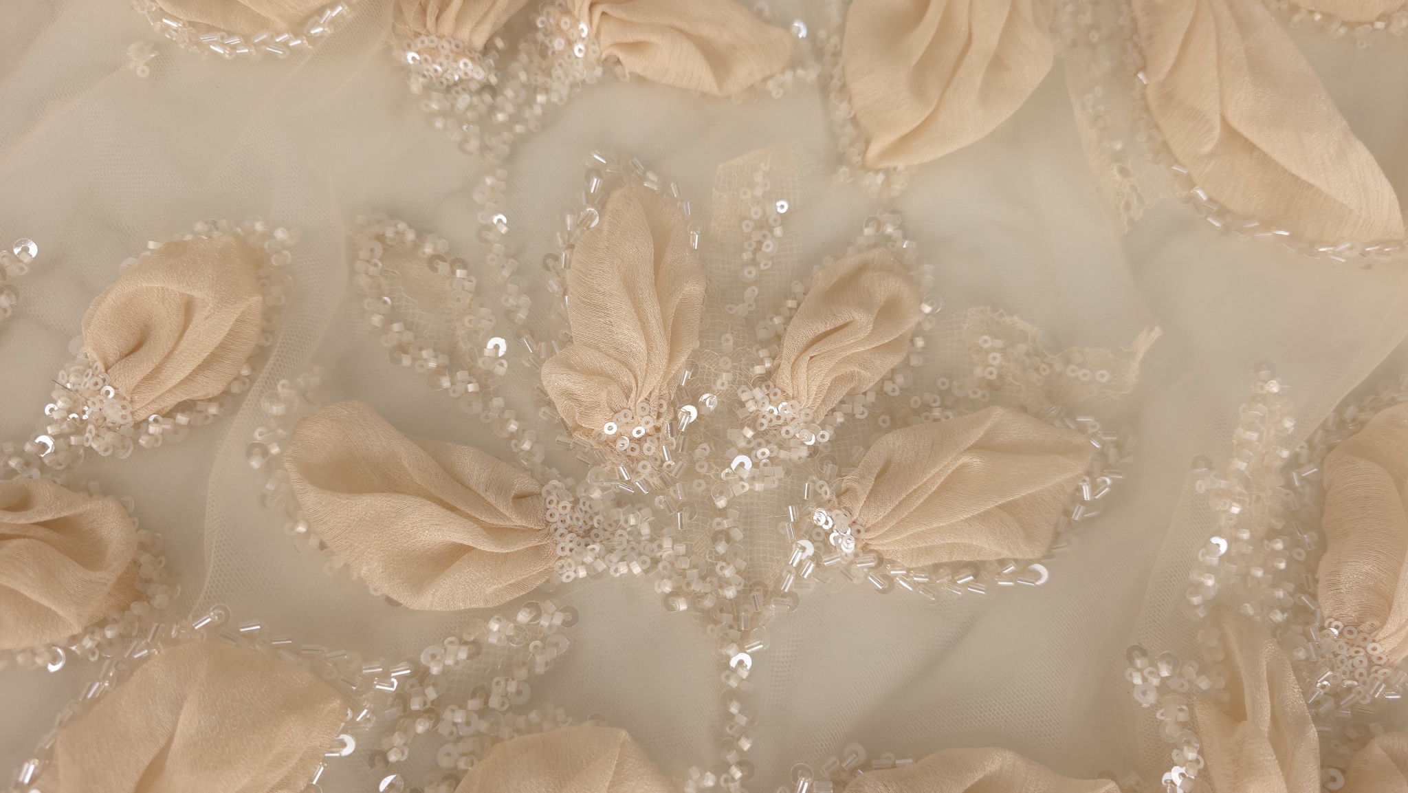 Mărgele tubulare transparente și paiete cusute între petalele peach ale broderiei 3D