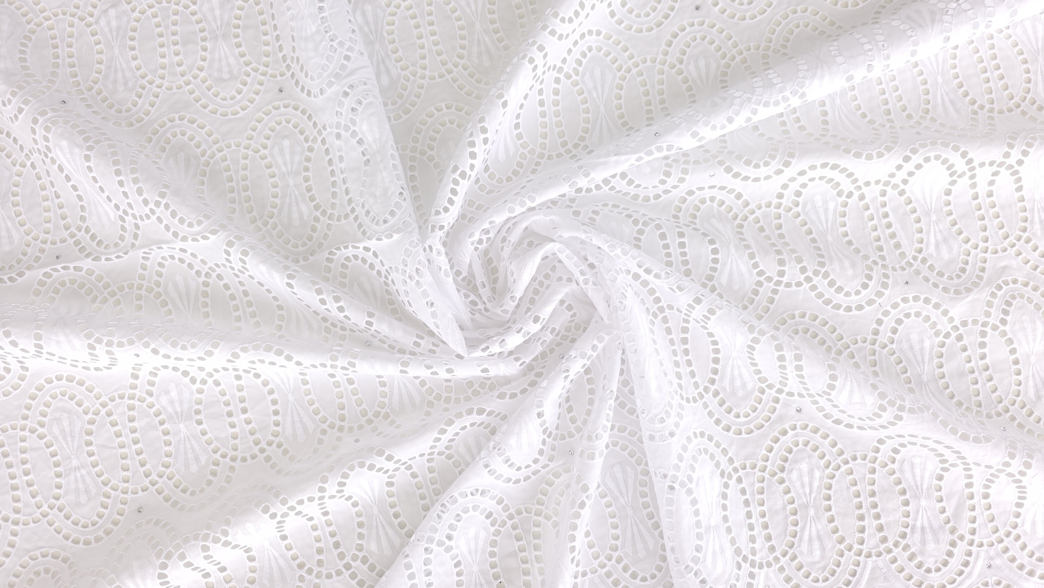 Margine ondulată a dantelei brodate albe ținută între degete, cristal vizibil