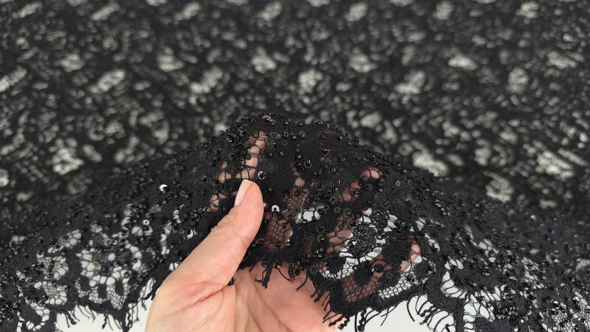 Marginea ondulată cu franjuri fine pe fond de tul negru transparent