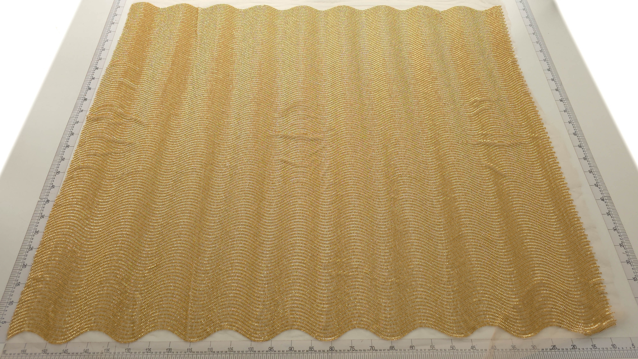 Material auriu desfășurat pe toată lățimea cu bordura scalopată pe margine