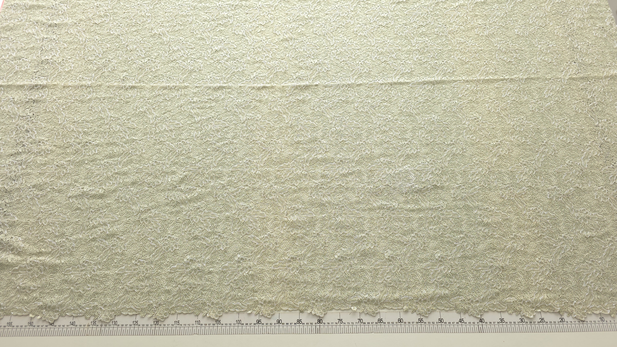 Material brodat cu bordură ondulată dublă desfăcut pe masă de tăiere cu riglă gradată