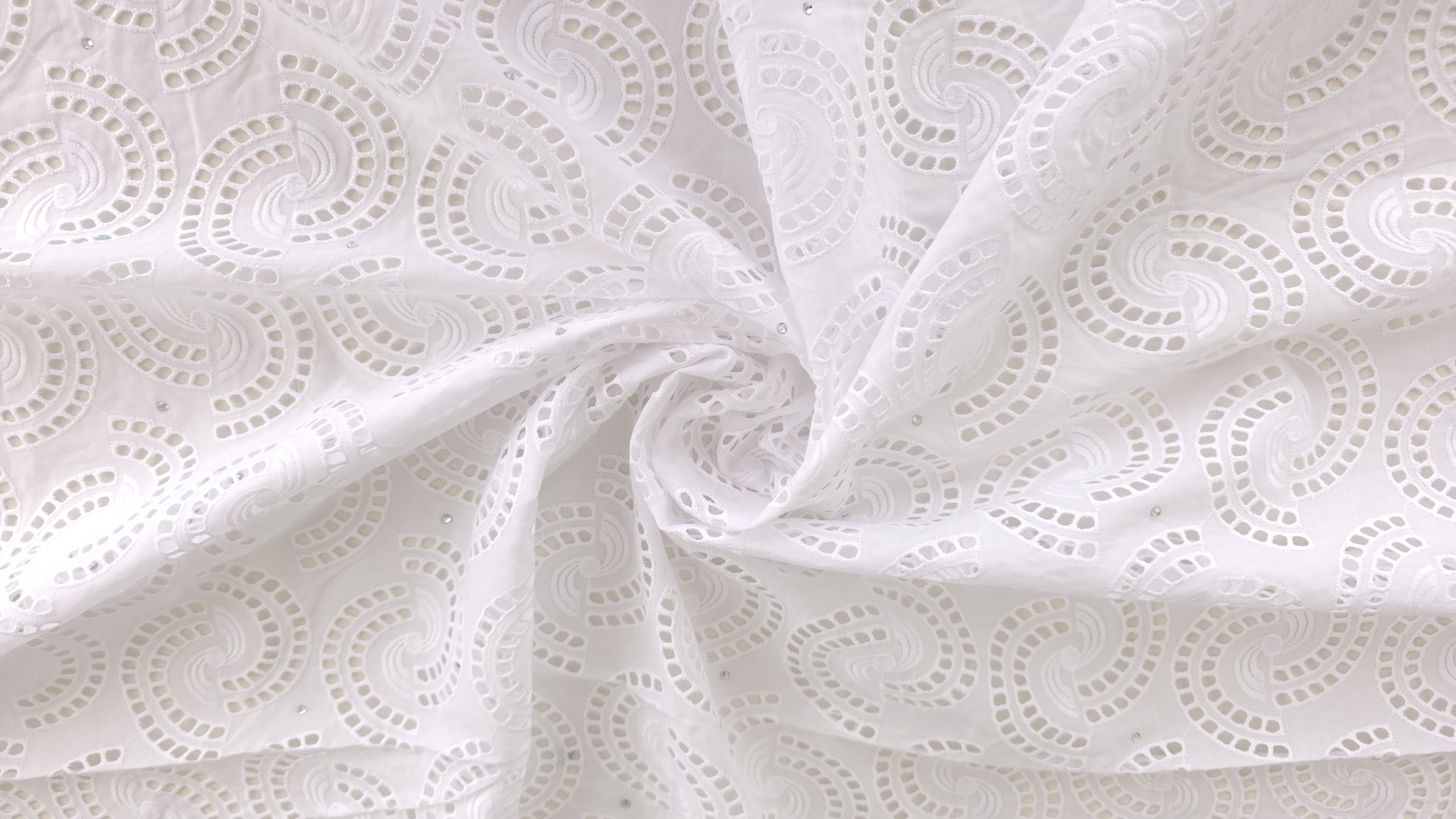 Material brodat cu decupaje spartă alb, falduri moi cu bordură ondulată vizibilă în plan lateral