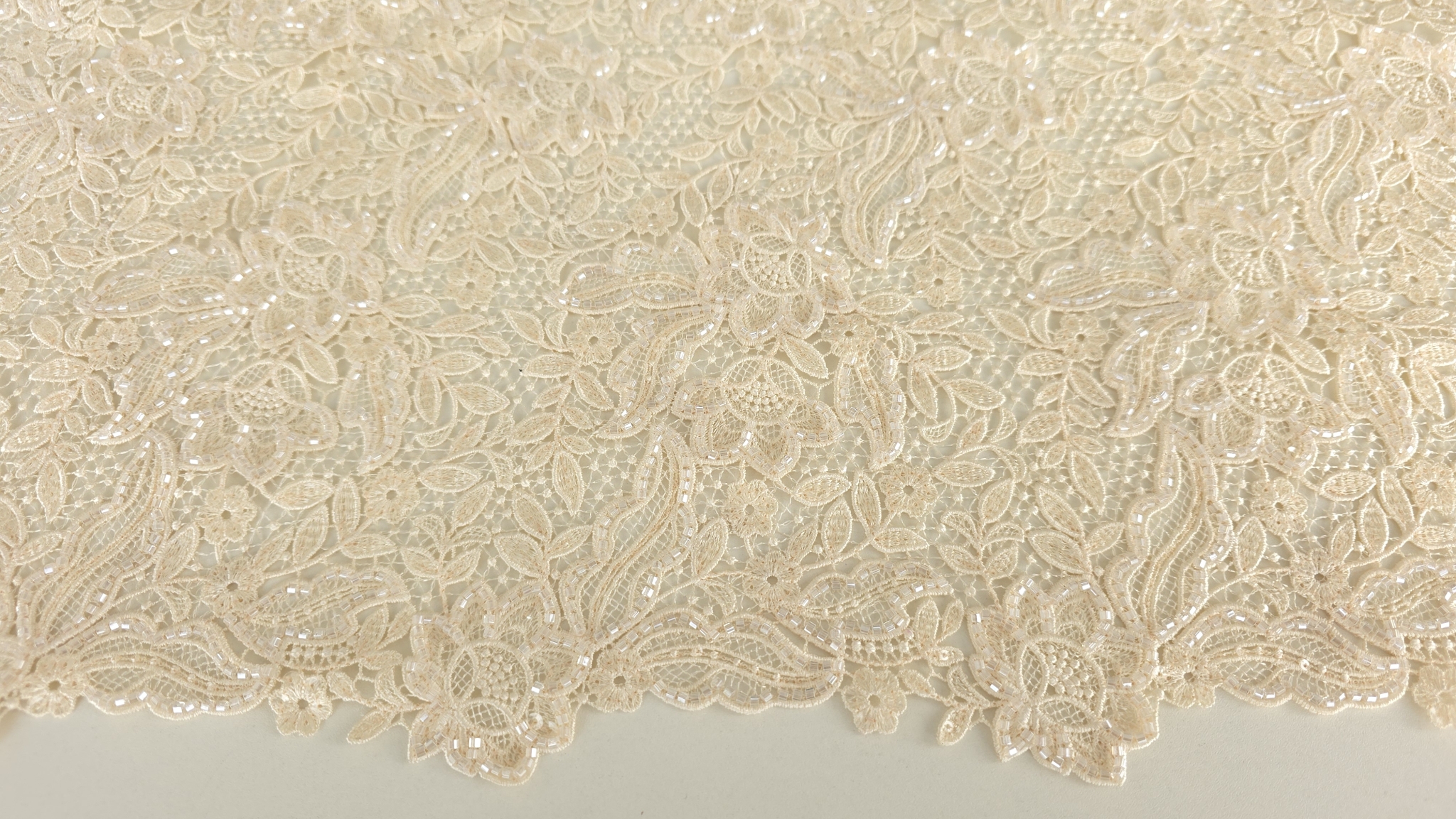 Material brodat formând falduri cu bordura ondulată vizibilă pe margine