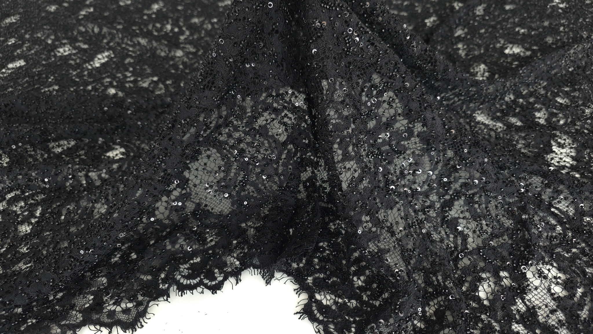 Material brodat negru cu aplicații văzut din unghi lateral cu bordura eyelash vizibilă