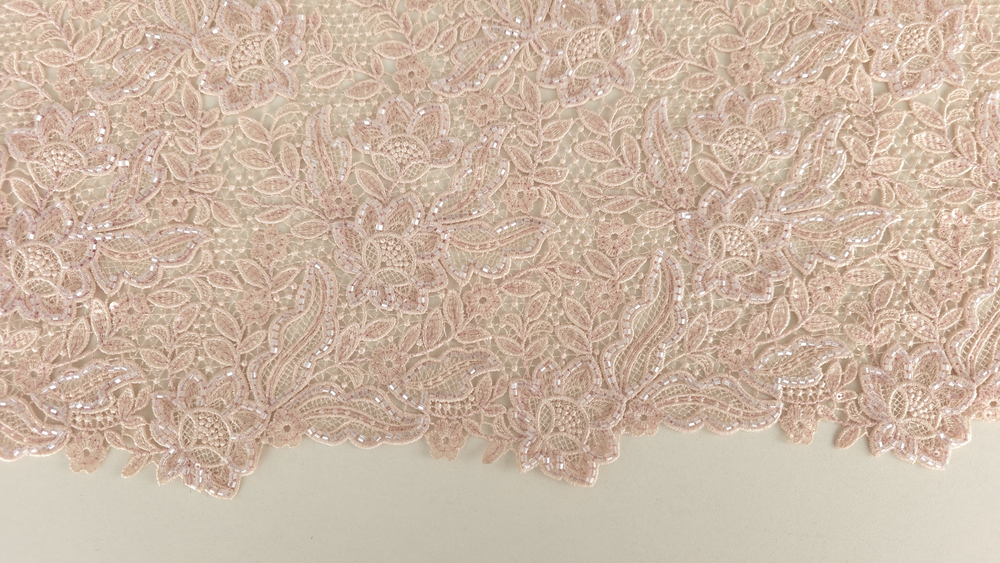 Broderie florală roz deschis cu bordură dublă vizibilă pe marginea materialului