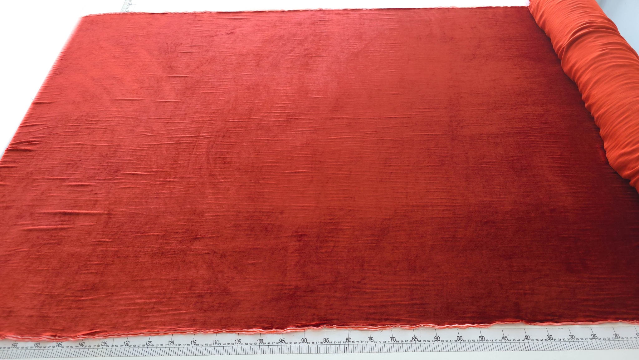 Material catifea grenadine întins pe masa de croire cu centimetru la margine