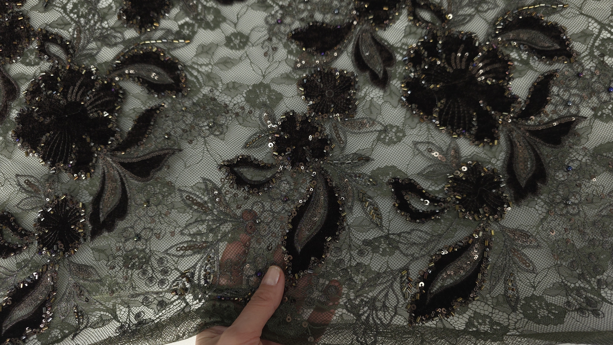 Material cu flori maro și margele pe tulle verde, plan mediu