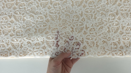 Material cu mărgele și paiete la metru ținut în mână pentru a arăta transparența