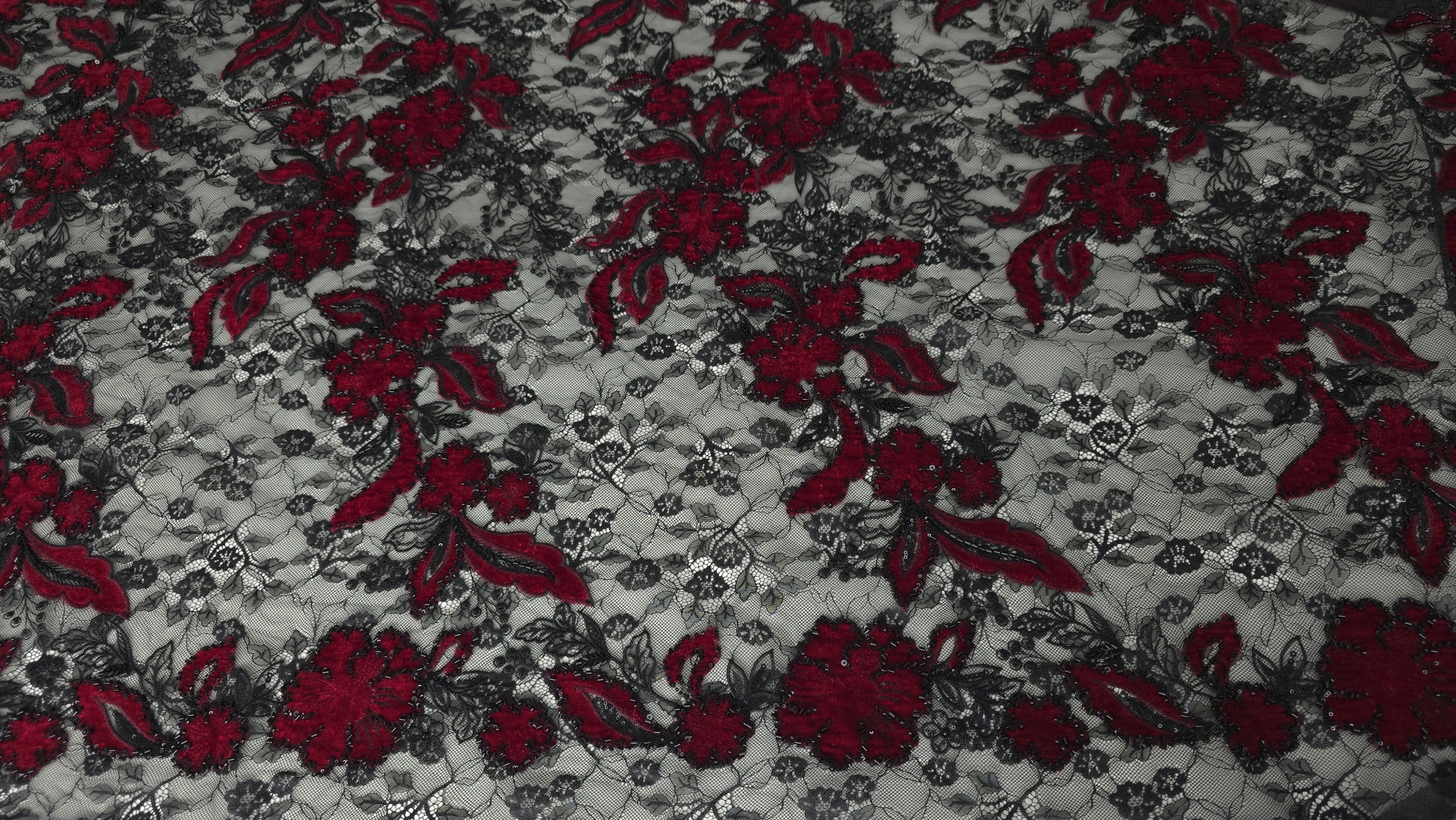 Material cu motive florale roșii și negre distribuite uniform pe toată suprafața