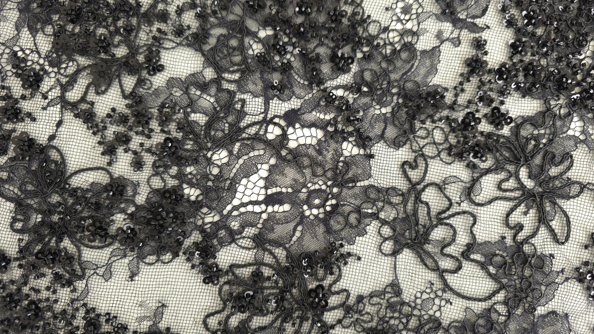 Material tip chantilly negru cu rebrodare margele și paiete desfăcut pe suprafață