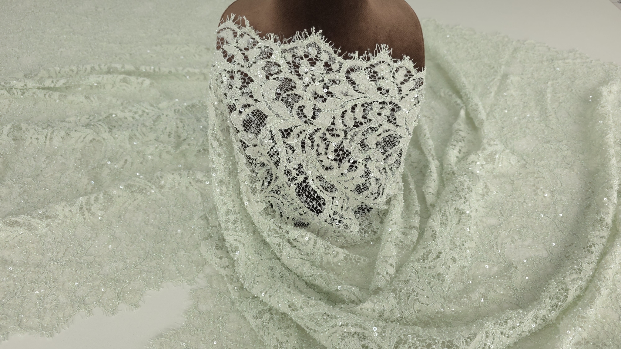 Material verde pastel pe manechin, vedere laterală cu bordură vizibilă