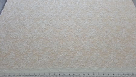 Metraj Chantilly ivory pentru rochii de mireasă desfăcut pe masă de tăiere cu riglă gradată