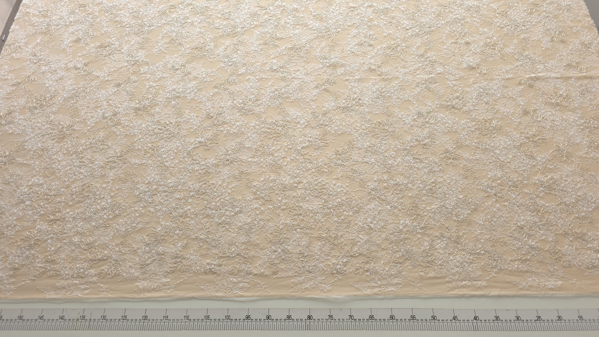 Rolă de material desfăcută pe masă de tăiere cu riglă gradată, vedere de ansamblu