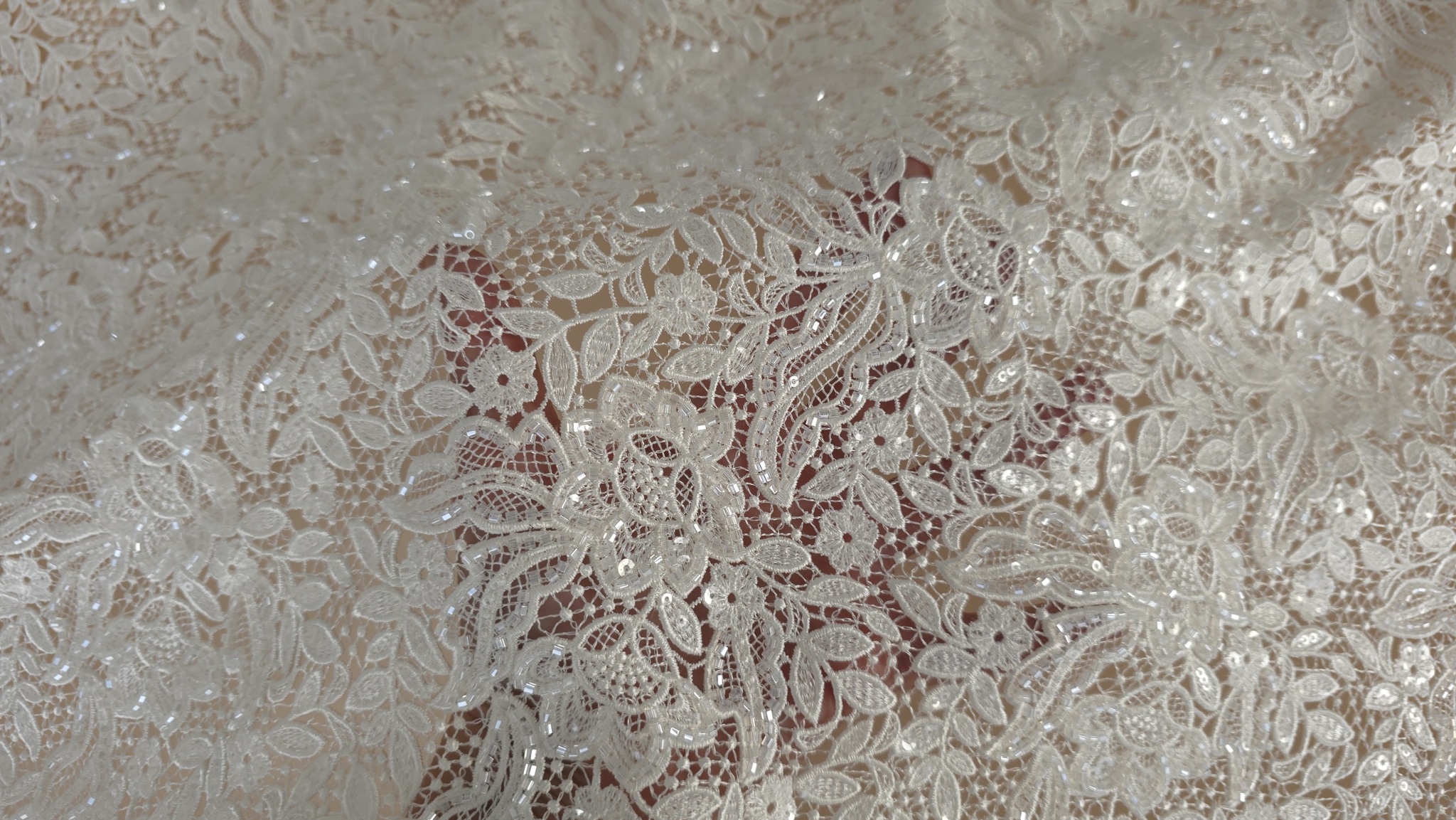 Suprafață brodată ivory cu puncte de strălucire vizibile între motive florale