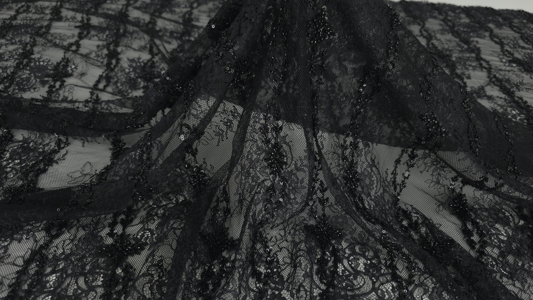 Suprafața dantelei negre cu micropaiete aplicate de a lungul motivului floral vegetal