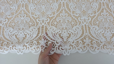 Suprafață de dantelă brodată ivory cu motive repetitive simetrice văzută din unghi