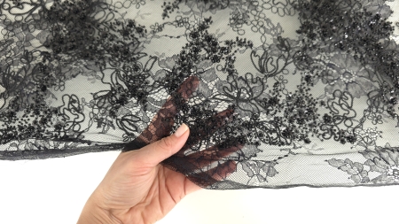 Suprafață de dantelă neagră cu motive florale dense și aplicații strălucitoare pe contururi