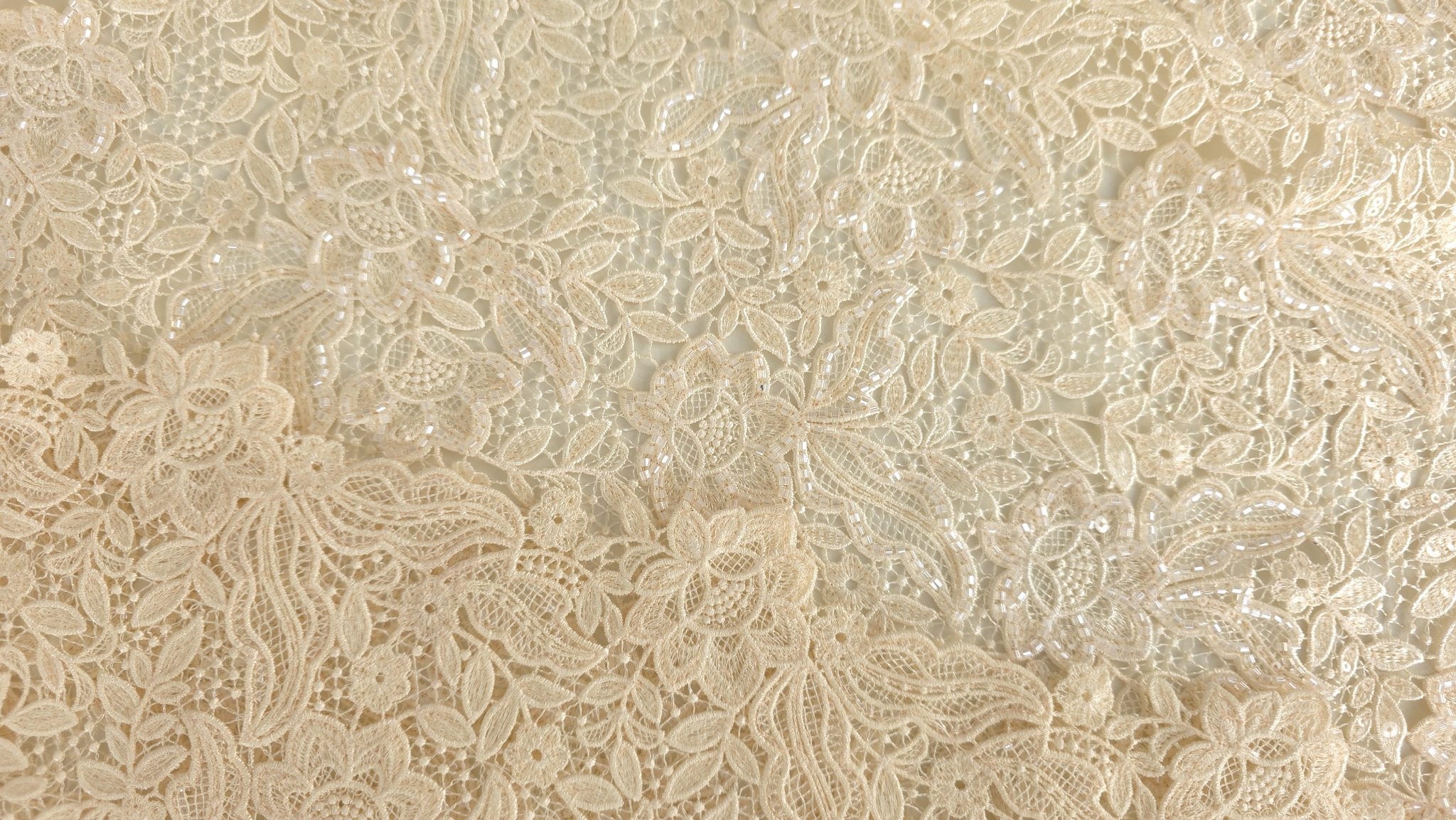 Suprafață textilă cu motive florale dense și mărgele transparente pe contururi