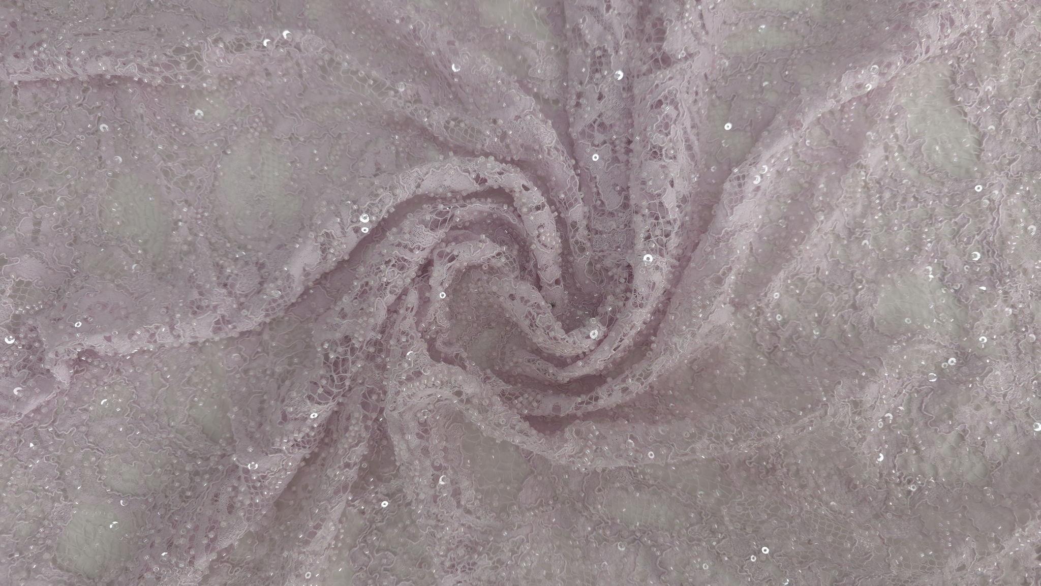 Suprafață textilă roz pastel cu broderie florală și aplicații din mărgele, plan general