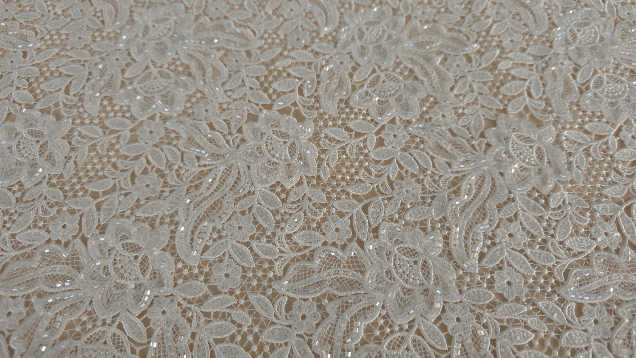 Țesătură brodată ivory cu aplicații strălucitoare fotografiată în lumină naturală