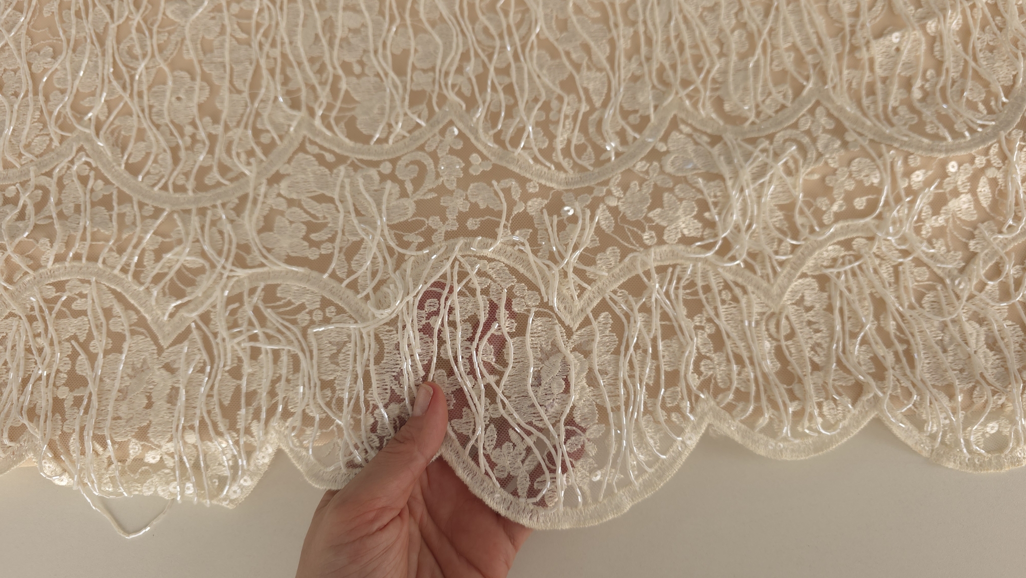 Transparența tullului brodat evidențiată prin ridicarea materialului cu șiraguri ivory