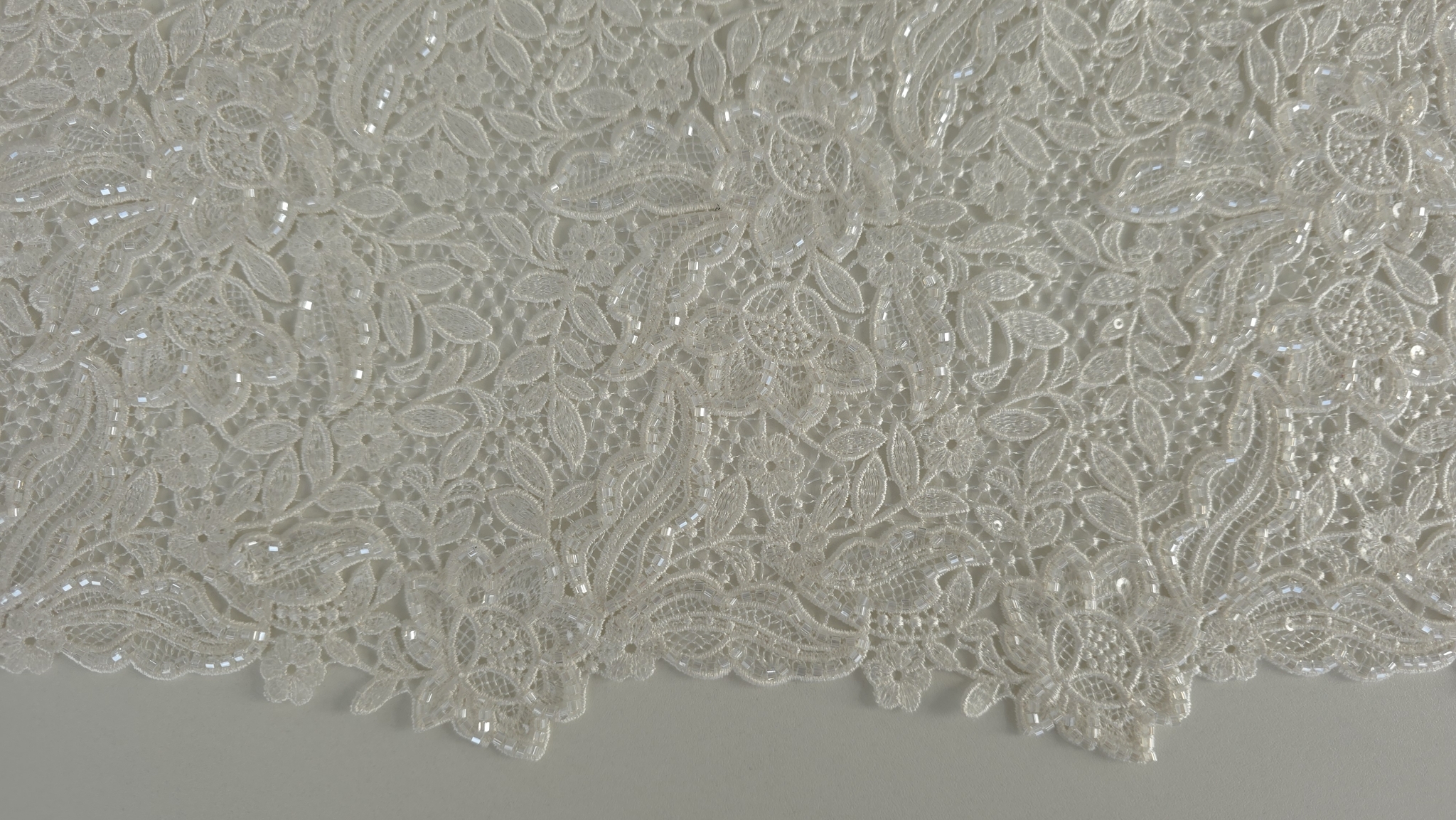 Vedere de ansamblu a broderiei ivory desfăcute pe masă de tăiere cu riglă gradată