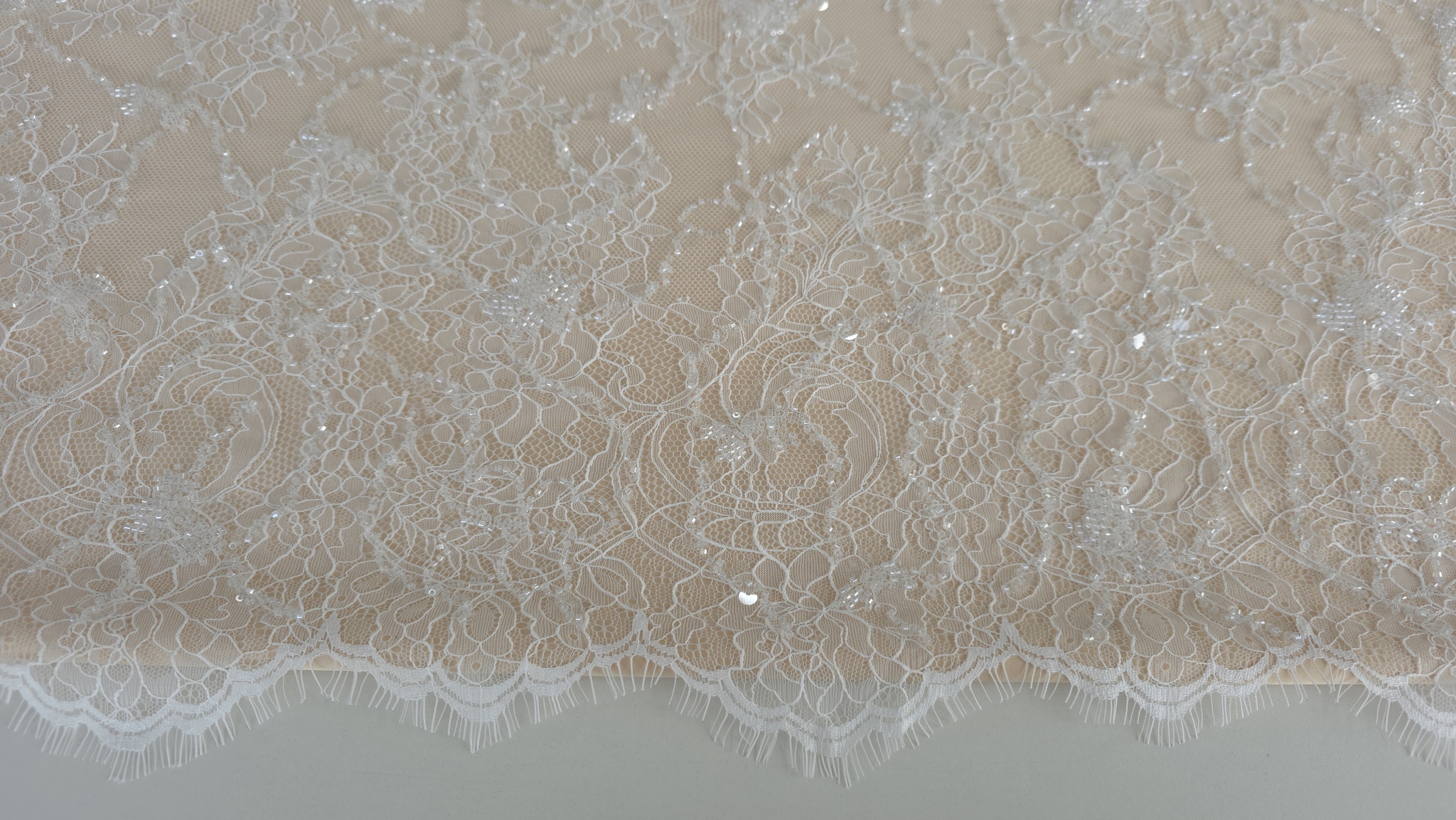 bordura festonata cu fire lungi decorative pe marginea materialului ivory